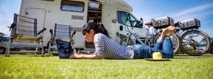 vrouw laptop bij camper en fietsen doorlopende reisverzekering